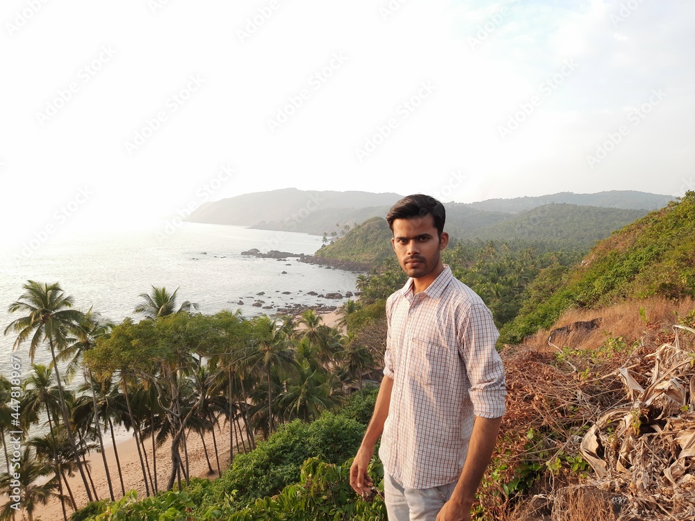 young man standing on the mountain, beautiful tropical sea coast with a person. goa beach.