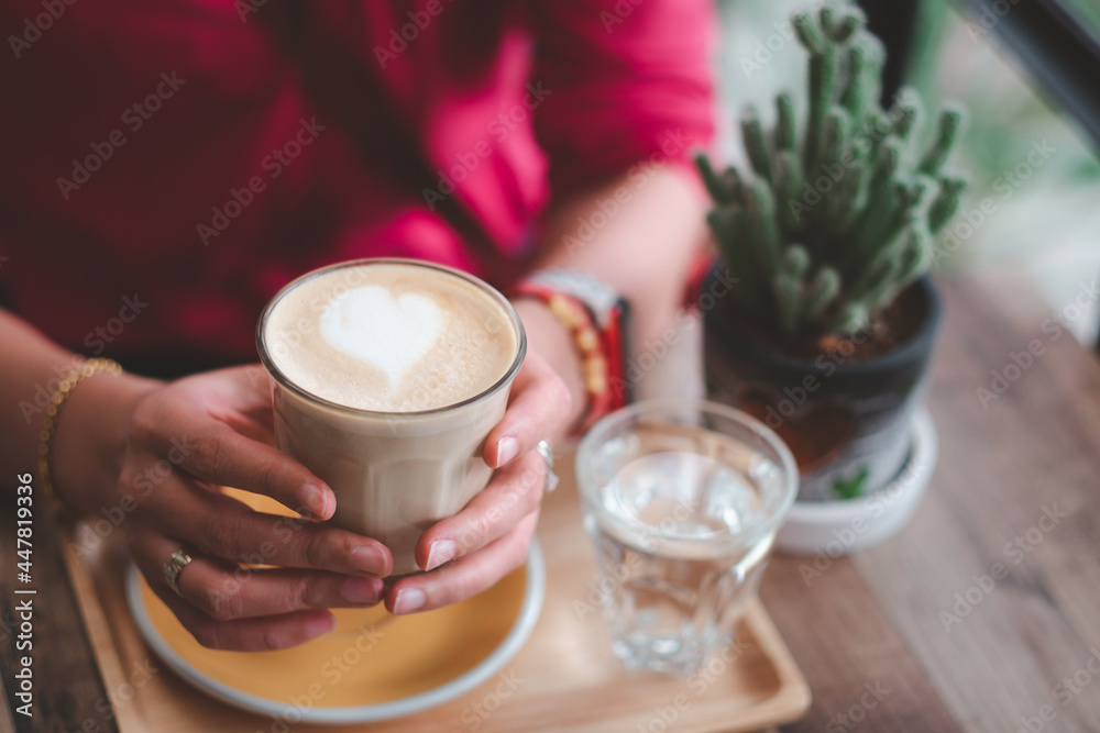 Obraz premium Female's hand holding cup of coffee on wooden table.