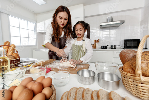 Asian mother kneaded dough happily and made desserts together in a modern kitchen at home.