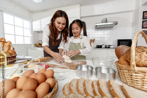 Asian mother kneaded dough happily and made desserts together in a modern kitchen at home.