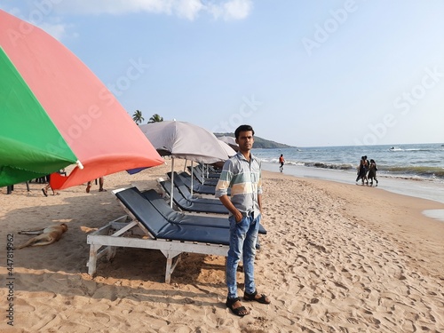 Man standingin  beach chair under the umbrella at Anjuna beach goa. Beach chairs with umbrella and beautiful sand beach, tropical beach with white sand. photo