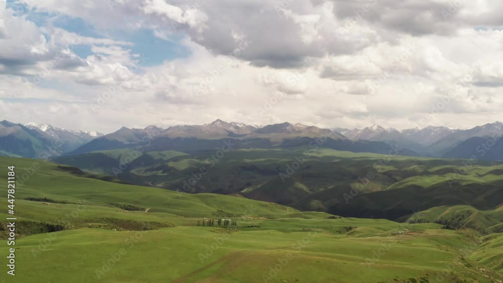 Mountain peaks and grassland are under white clouds. Mountain peaks and grassland are under white clouds.