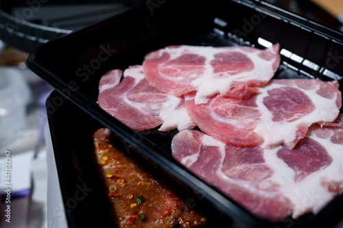 The lean pork cut into thin slices is placed in a black tray that looks appetizing.