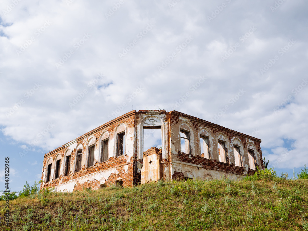 An old brick ruined building on a hill. Clouds in the sky