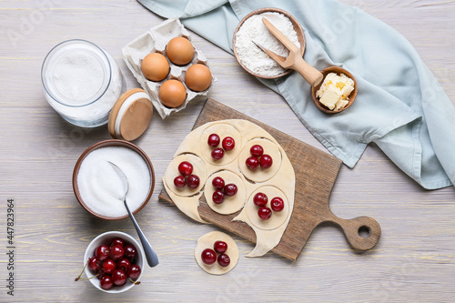 Composition with fresh dough for cherry dumplings on color wooden background