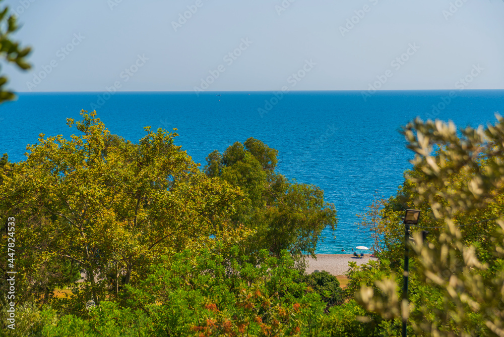 ANTALYA, TURKEY: Trees and the Mediterranean Sea, Konyaalti beach in sunny summer in Antalya.