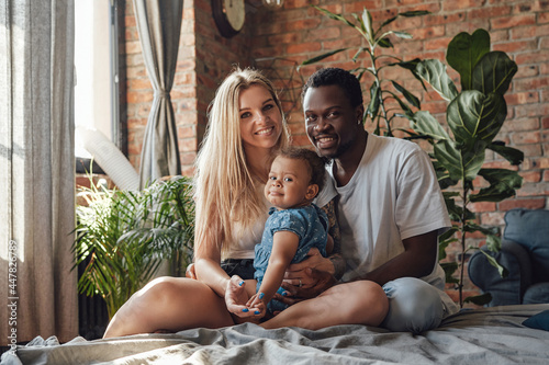 Multi ethnic couple and their baby having fun at home photo