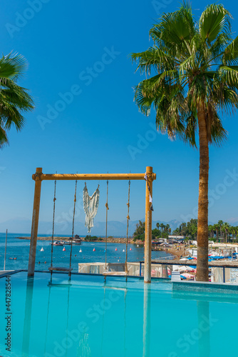 Fototapeta Naklejka Na Ścianę i Meble -  ANTALYA, TURKEY: Swimming pool and swing on the territory of Fosforlu beach on a sunny day.