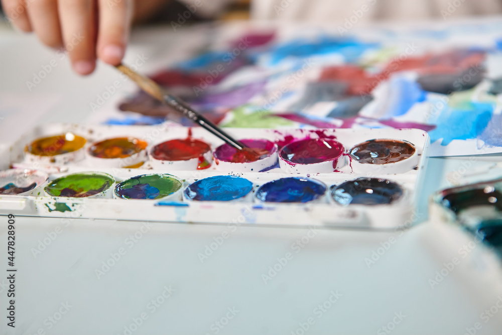 A boy draws with paints at a table in his room. High quality FullHD footageA boy draws with paints at a table in his room. A boy draws with paints at a table in his room. High quality FullHD footageA boy draws with paints at a table in his room.