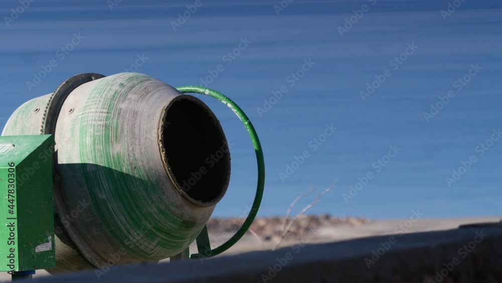 Concrete mixer machine mixing cement on construction building site works area near sea. Industrial work equipment. Concrete mixer machine mixing cement on construction building site works area near sea. Industrial work equipment.