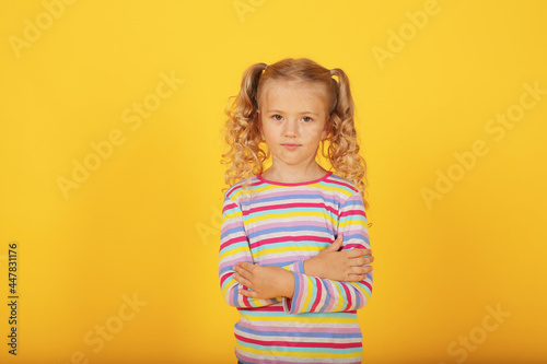 a beautiful blonde girl with ponytails and a multi-colored T-shirt shows emotions