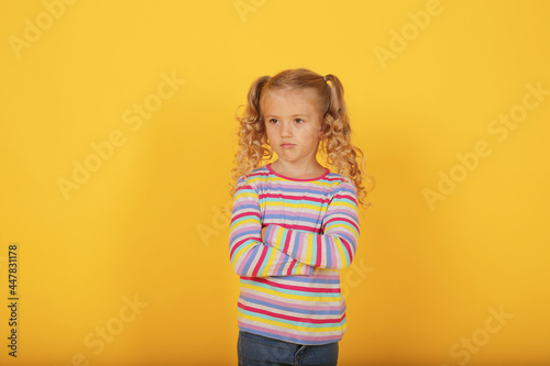 a beautiful blonde girl with ponytails and a multi-colored T-shirt shows emotions