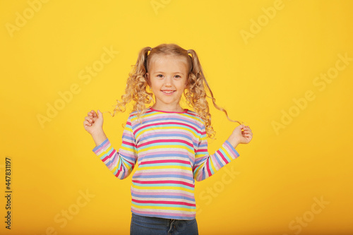 a beautiful blonde girl with ponytails and a multi-colored T-shirt shows emotions