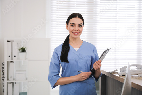 Receptionist with clipboard at countertop in hospital