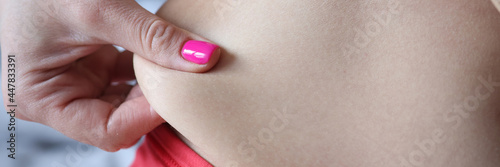 Woman hand wrapping around fat fold on abdomen closeup