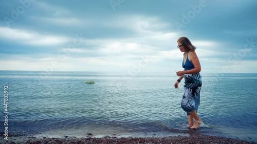 Senior Woman Walking At The Beach In Karkle, Lithuania - wide, slow motion photo