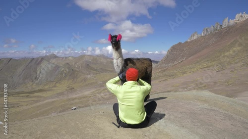 male model taking photos of llama glama in the rainbow 7 colors Mountains of Cusco, Peru photo