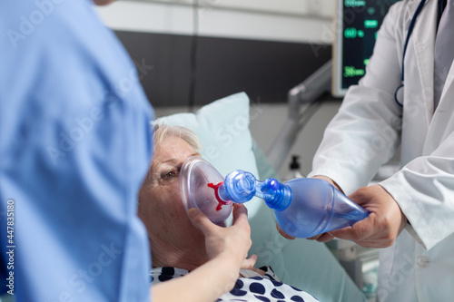Bild auf Leinwand Doctor and nurse helping sick hospitalized senior woman breath, with ambu bag during resustacitor process, due to lung infection, iv drip bag attached