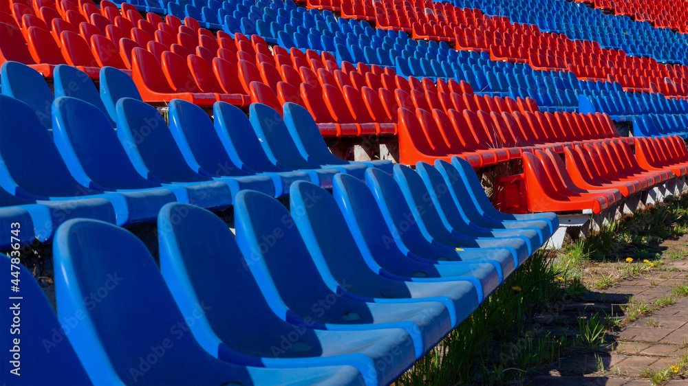 Fototapeta premium Plastic seats in red and blue in the old stadium