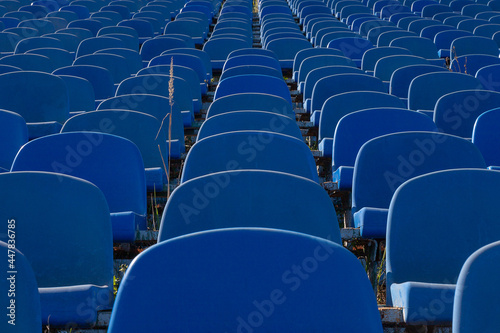 Blue plastic chairs stand in rows in the old stadium