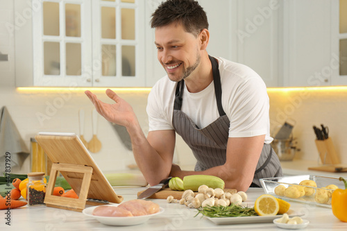 Man watching online cooking course via tablet in kitchen