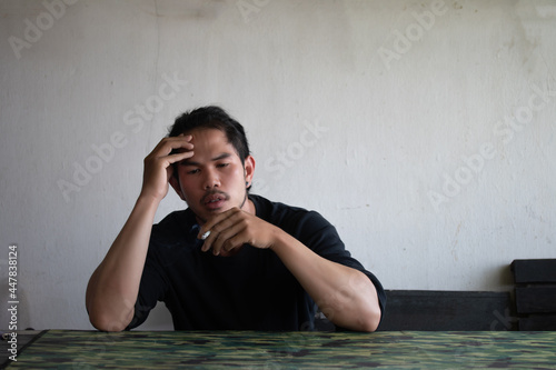 Depressed and hopeless asian man sitting alone after using drugs sitting on the floor. Drugs addiction and withdrawal symptoms concept. photo