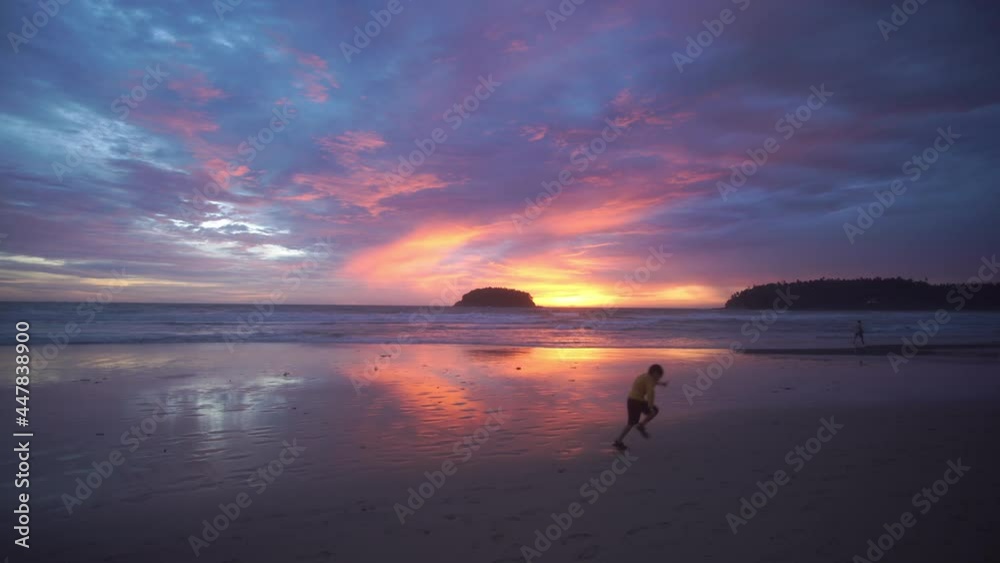 A happy boy running on the beach in stunning sunset..4K UHD Beautiful tropical beach with blue sky and colorful clouds. .Tropical beach with waves crashing empty beach iin Phuket Thailand.. A happy boy running on the beach in stunning sunset..4K UHD Beautiful tropical beach with blue sky and colorful clouds. .Tropical beach with waves crashing empty beach iin Phuket Thailand..