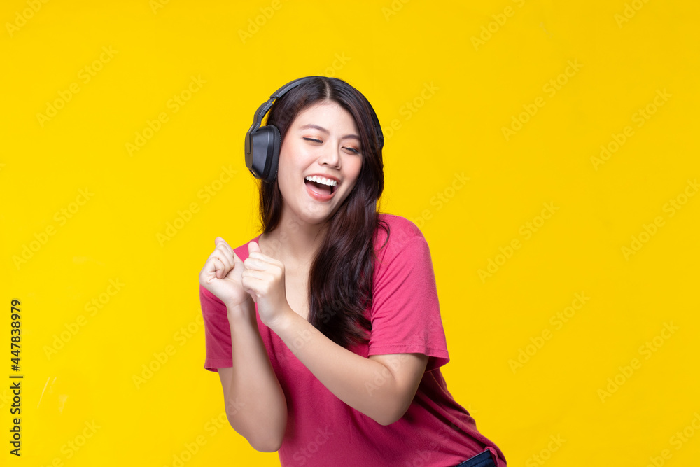 Portrait of beautiful young asian woman dancing and listening to music having fun in summer on yellow background. Portrait of beautiful young asian woman dancing and listening to music having fun in summer on yellow background.