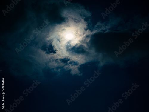Full moon among clouds in the night sky.