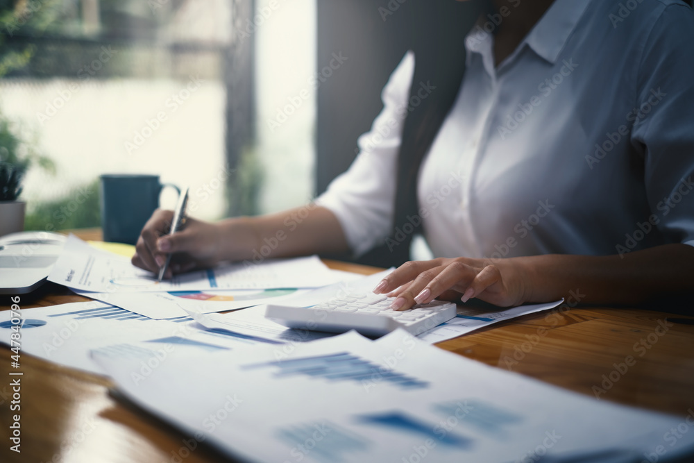 Close-up of a businesswoman using a calculator to audit the company's budget. Tax information is calculated by accountants Close-up of a businesswoman using a calculator to audit the company's budget. Tax information is calculated by accountants