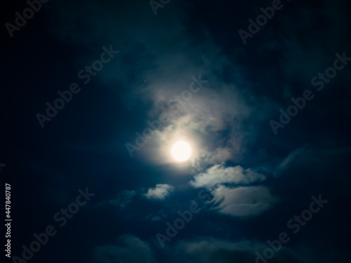 Full moon among clouds in the night sky.