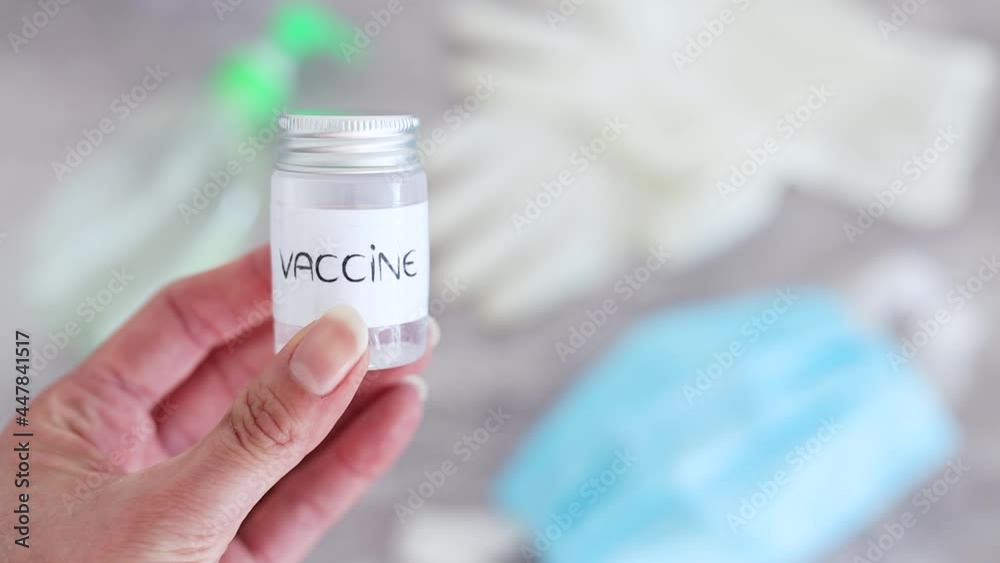covid-19 vaccine race, hand holding vaccine ampooule with disposable gloves, hand sanitizer and face mask in the background covid-19 vaccine race, hand holding vaccine ampooule with disposable gloves, hand sanitizer and face mask in the background