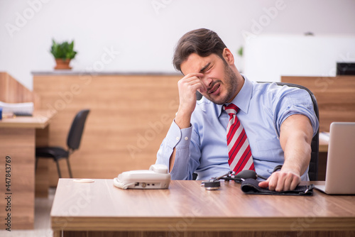 Young male employee suffering from hypertension at workplace photo