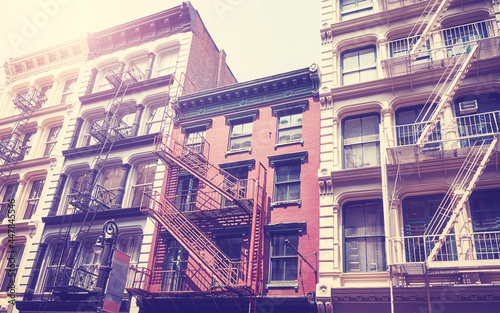 New York old townhouses with iron fire escapes, color toning applied, USA.