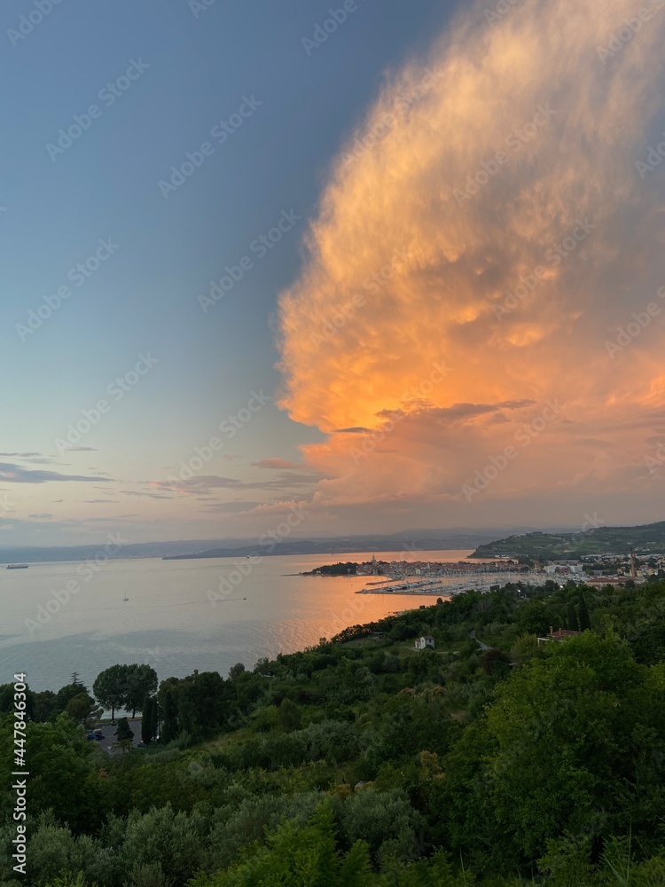 Scenic view to the amazing red sunset at the Adriatic sea, coast in Slovenia at summer. View to green hills and olive trees. Izola. Natural backgrounds. 