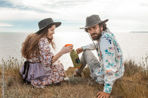 Man and woman drink coffee pouring from thermos being on top of a hill in summer