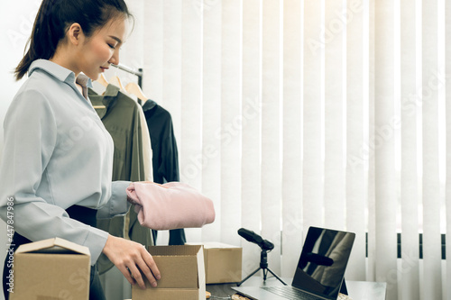 Asian entrepreneur is preparing her clothes that can be sold in paper boxes for delivery to customers. photo