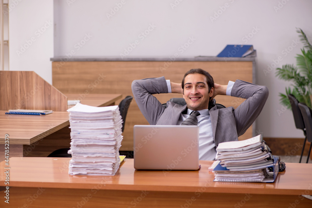 Young male employee and too much work in the office Young male employee and too much work in the office