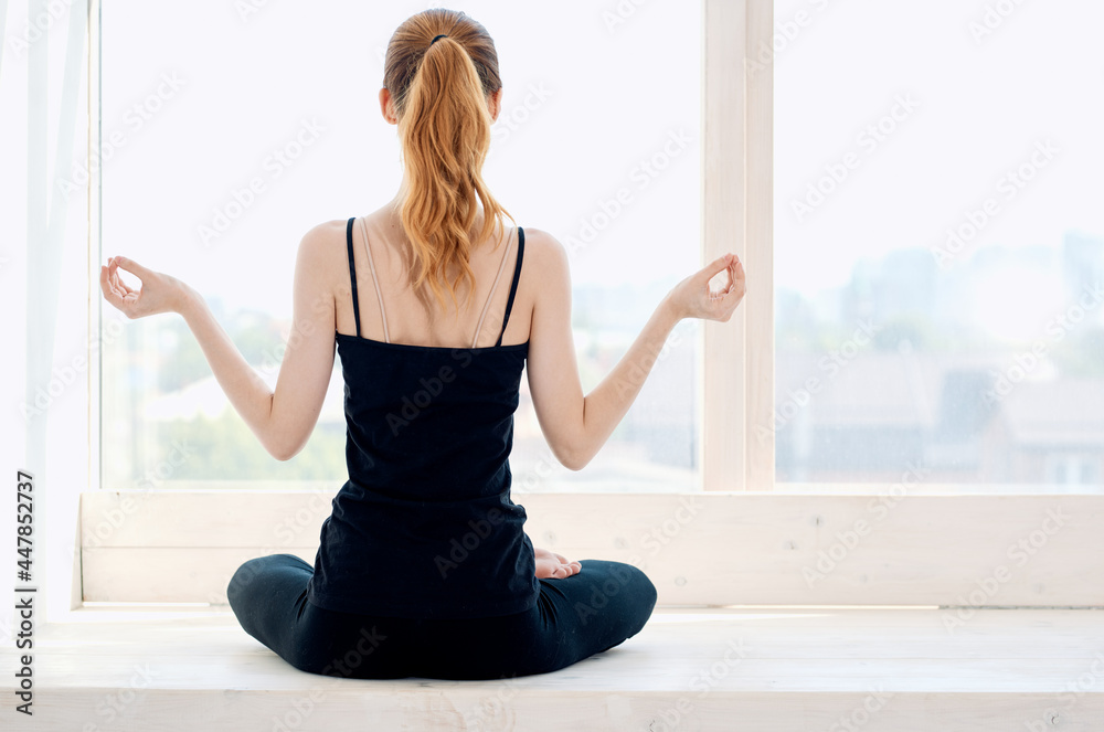 woman sitting in lotus position exercise meditation yoga near window