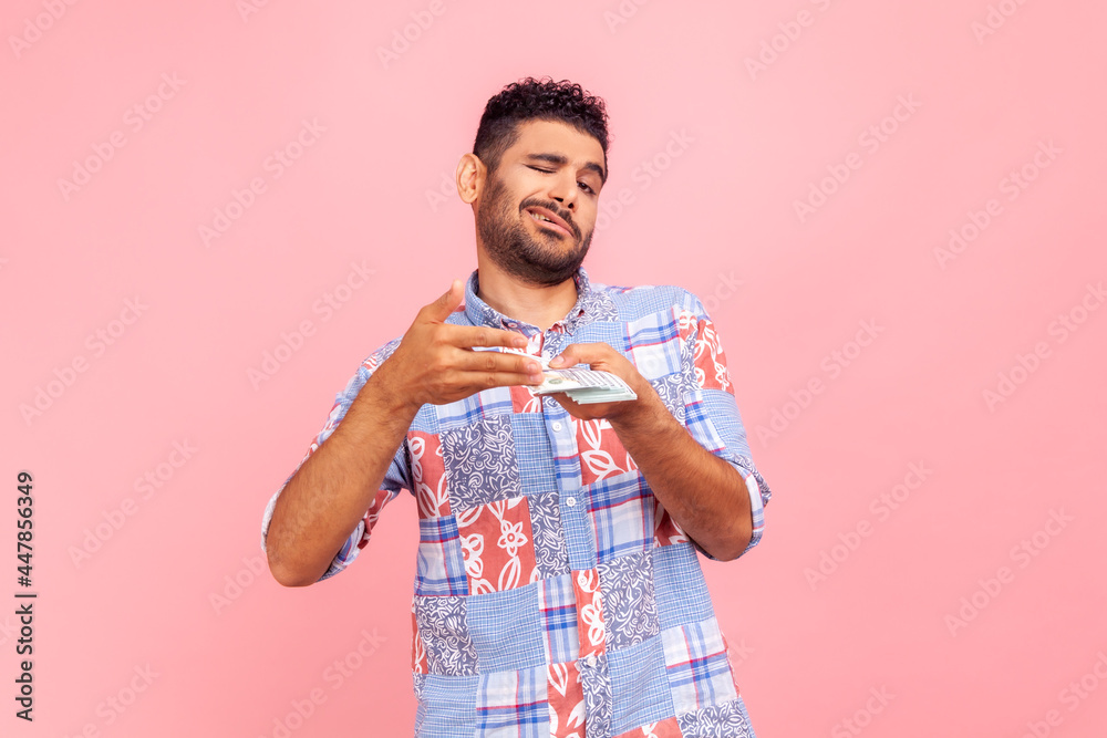 Profile portrait of self confident young adult handsome man with beard scattering dollars with proud facial expression, rich satisfied guy, Indoor studio shirt isolated on pink background. Profile portrait of self confident young adult handsome man with beard scattering dollars with proud facial expression, rich satisfied guy, Indoor studio shirt isolated on pink background.