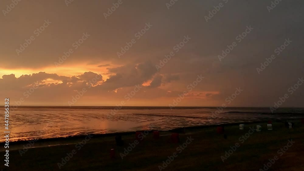 thunderstorm and orange clouds at the horizon at the North Sea thunderstorm and orange clouds at the horizon at the North Sea