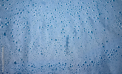 Photo of the texture of round water drops on a plastic film with a blue background