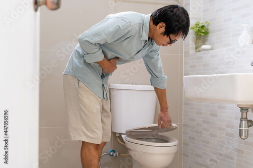 Men are standing in front of the bathroom door using their hands to hold the abdomen with severe abdominal pain or diarrhea. The concept of stomach cramps, diarrhea