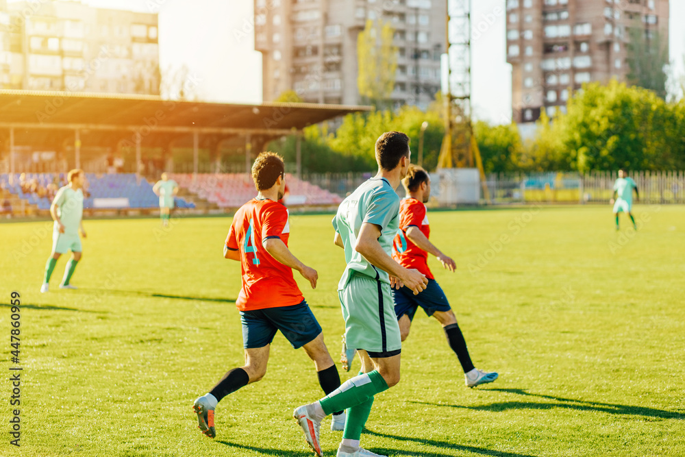 Obraz premium football players in action at the stadium, Football game for adults, Players of two teams competing for the ball