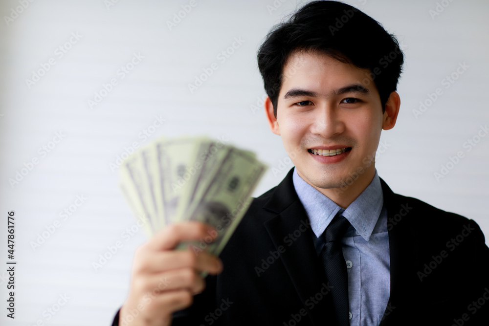 Selective focus on Asuab businessman holding dollar bank notes or money with blur foreground. Financial Concept. Selective focus on Asuab businessman holding dollar bank notes or money with blur foreground. Financial Concept.