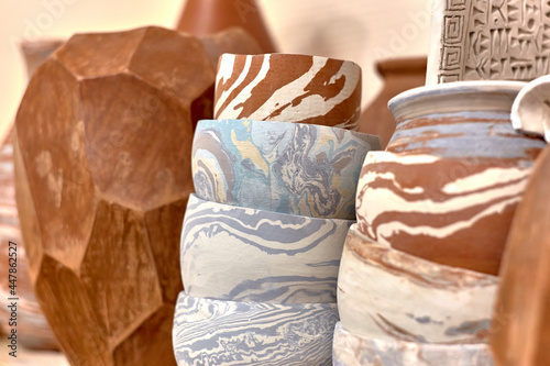 A stack of ready-made ceramics using Japanese technique Nerikomi made of white, red and blue clay dries on a shelf
