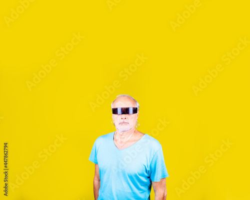Elderly caucasian man wearing smart sci-fi glasses on yellow background with advertising copyspace