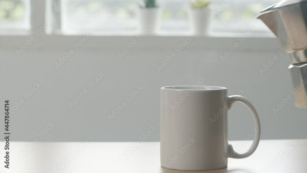 barista pouring Hot coffee in ceramic white coffee cup with smoke on wooden table in window background. Hot Coffee Drink Concept barista pouring Hot coffee in ceramic white coffee cup with smoke on wooden table in window background. Hot Coffee Drink Concept