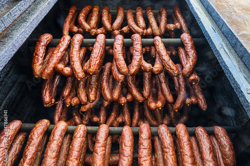 Photo Close-up of smoked sausages from pork and beef meat hanging inside a wooden smokehouse