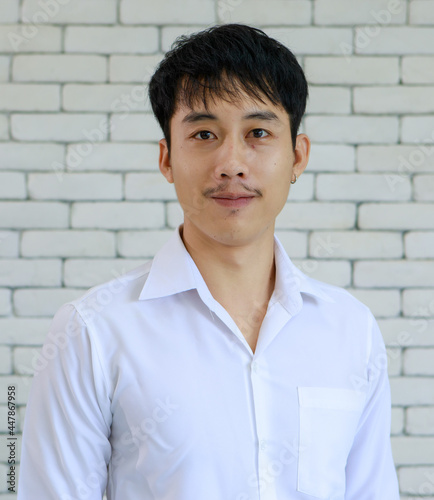 Portrait of young and handsome Asian man with beard pose smile and happy friendly face on white brick wall background